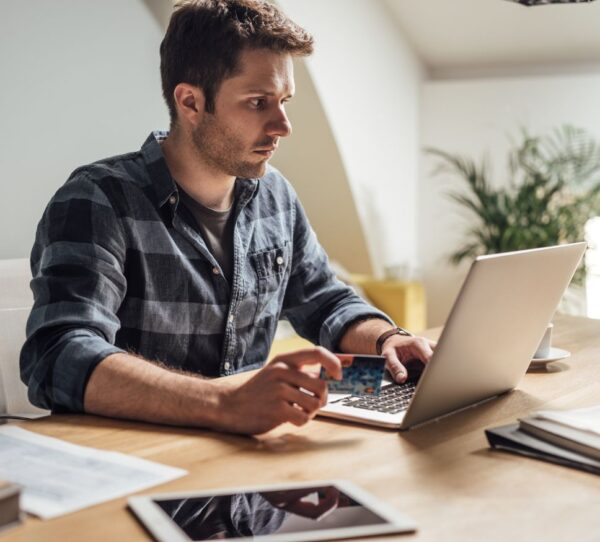 Financial Adviser Perth - Man focused in front of laptop holding card showing control and financial awareness