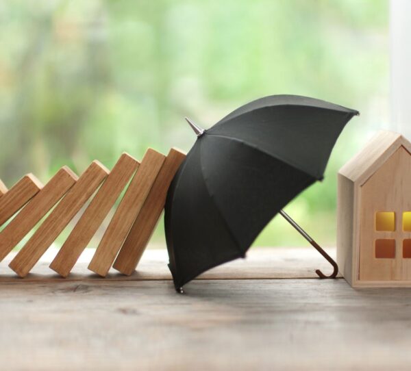 Financial Adviser Perth - Umbrella stopping falling dominoes from hitting house showing risk prevention and stability