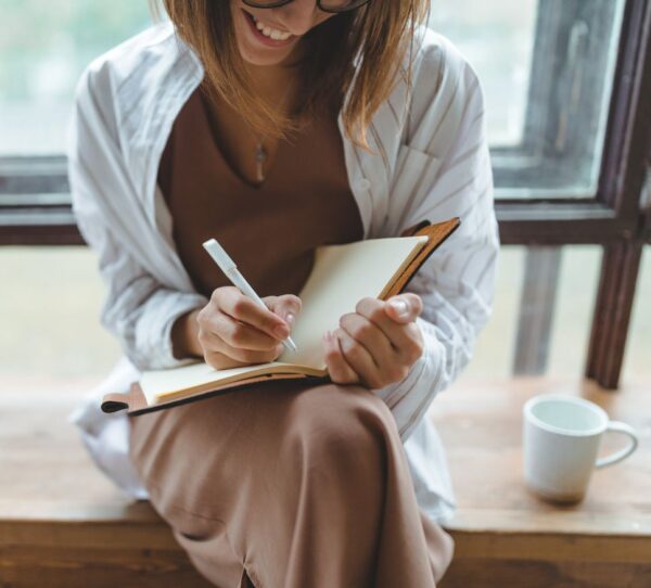 Financial Adviser Perth - Woman writing happily on checklist showing self reflection and life focus